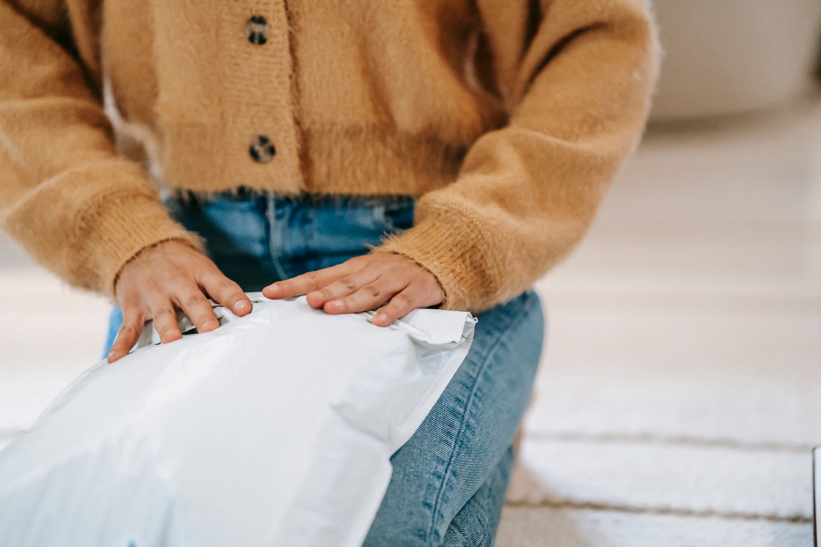 Unrecognizable female unpacking parcel bag in apartment