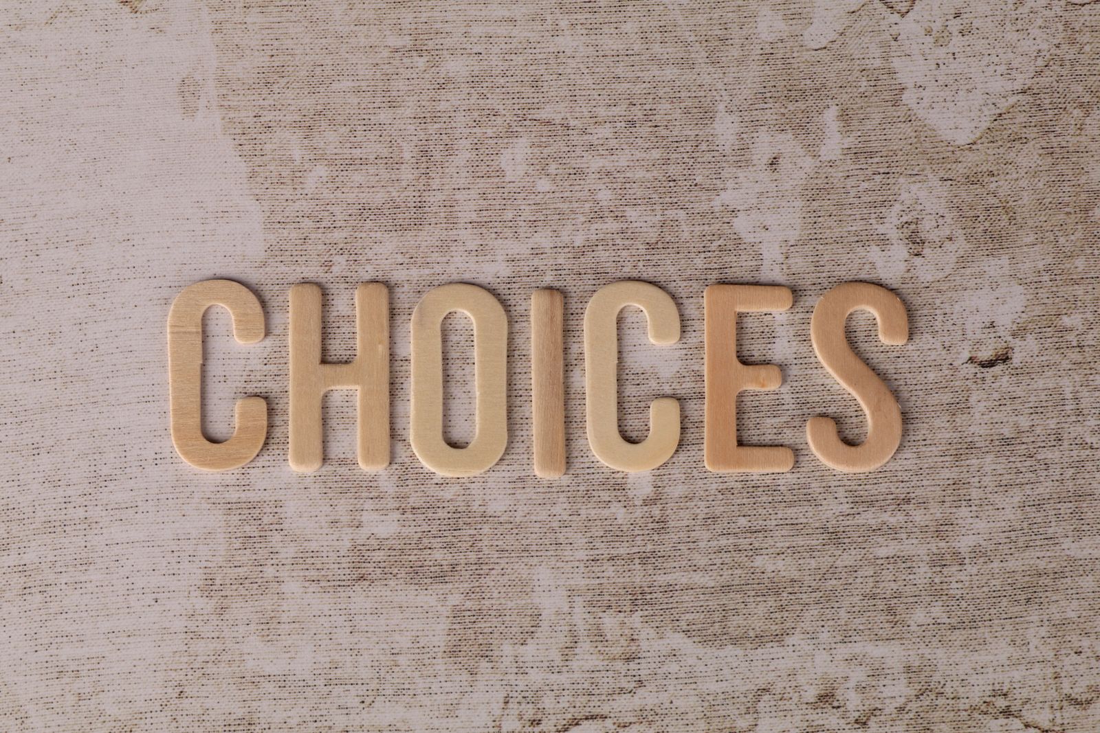Wooden letters spelling choices on textured surface